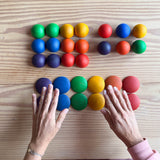 Hände über den 30 Teilen von Grapat buntes Rundes "Round" mit 12 Halbkugeln, 12 Buckelplättchen und 6 Kugeln in Regenbogenfarben.