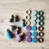 Grapat Holzfiguren-Set "Aquamarina Winter", alle 45 Teile aufgelegt: 6 Nins Holzfiguren mit oder ohne Hut, 3 Töpfchen, 9 Rings und 9 Coins in blau, lila und grau.