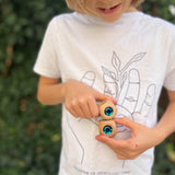 Ein Kind hält zwei Glitzerwürfel mit türkisen Glitzersteinen von Nic Toys aufeinander gestapelt in den Händen.