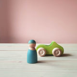 Grimms Holzauto grün, daneben eine blaue Spielfigur aus Holz.