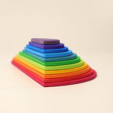 Grimms Regenbogen Bauplatten übereinander gestapelt zu einer Halbkreis-runden Pyramide schräg an der Kante fotografiert.