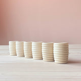 Sechs Stück Grapat "Beehive Cups" gerillte Holzbecher für freies Spiel nebeneinander gestellt.