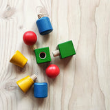 Schrauben und Muttern aus Holz von Nic Toys in den Farben rot, gelb, grün und blau einzeln auseinander geschraubt.