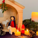 Ein Blick in eine Weihnachtskrippe für Kinder, mit Maria, zwei kleinen Filzschafen, einem kleinem roten Holzzwerg von Grapat als Hirte, davor Teelichter und eine Strohstern.