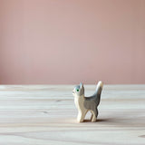 Eine Spielfigur aus Holz, nämlich eine grau-weiße Katze steht auf einer Holzplatte und schaut nach links.