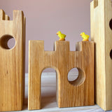 Ein kleines Burgtor aufgebaut mit den Ritterburg Bausteinen aus Holz von Bauspiel, auf den Zinnen sitzen zwei gelbe Ostheimer Küken.
