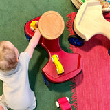 Ein Baby spielt mit kleinen gelben Holzautos auf dem roten Rutschauto von Lautenbach .