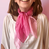 Ein Mädchen mit einem pinken und einem rosa Seidentuch um den Hals gebunden.