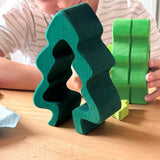Der größte Teil des Steckspiels Tanne stehen ganz vorne, dahinter spielt ein Kind mit den anderen Teilen.