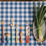 Die Wrkzeuge des Grapat "Tools" Handwerkzeug Spielset aus Holz liegen auf einem blau karierten Tischtuch.