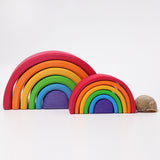 Der kleine Regenbogen von Grimms in den klassischen sechs Regenbogenfarben. Daneben liegt das Haus einer Weinbergschnecke zum Größenvergleich, dahinter steht der große Regenbogen von Grimms.