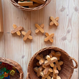 Fünf X-Klötze Holzbausteine liegen auf dem Boden, daneben Weidenkörbe gefüllt mit X-Kötzen und Lichtwürfel von Bauspiel.