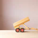 Der Fagus Anhänger für den Muldenkipper aus Holz, seitlich, angehängt an eine Zugmaschine, die Ladefläche mittelmäßig, in der zweiten Position, hochgekippt.