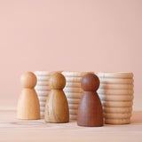 Die Holzfiguren Grapat "3 Nins, 3 Woods" Freunde Natur stehen vor drei gerillten Holztöpfchen von Grapat.