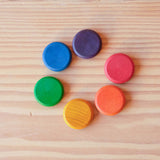 Die Grapat Coins Holzplättchen in den sechs bunten Regenbogenfarben liegen im Kreis.