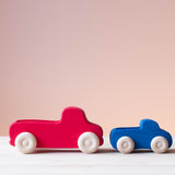 Grimms großer Lastwagen in rot und Grimms kleiner blauer Lastwagen hintereinander.
