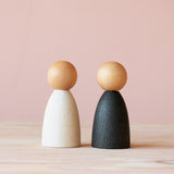 Die Grapat Adult Nins mit hellem Holz, zwei Spielfiguren in weiß und schwarz, mit einem hellen kugeligen Holzkopf.