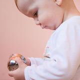 Ein Baby hält zwei Kinder Klangschalen in den Händen, setzt sie ineinander und schaut konzentriert darauf.