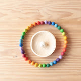 Die 36 Stück Grapat Mandala Regenbogen Eier farblich in einem Kreis aufgestellt, in der Mitte eine Weidenwackelschale mit einem Schneckenhaus.