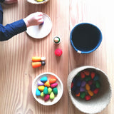 Körbe und Schalen mit Grapat Mandala Regenbogen Eier, ein Kind spielt gerade damit.