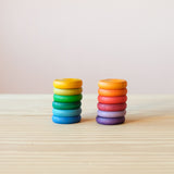Coins von Grapat in Regenbogenfarben: die 12 unterschiedlichen Farben sind sortiert in zwei Stapeln von je 6 Holzplättchen zu sehen.