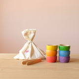 Grapat "Bowls and Acorns" Sortierspiel: hier sind die 36 kleinen Holzeicheln in ihrem Stoffsack versteckt, daneben die sechs Holzschälchen in Regenbogenfarben und die Holzschale-