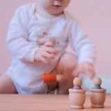 Ein Baby spielt mit Grapat Mates Holzbechern Natur und Grapat Nins Spielfiguren.