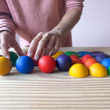 Erwachsene Hände spielen oder sortieren die Holzkugeln in Regenbogenfarben von Grapat buntes Rundes "Round".