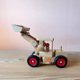 Der Fagus Radlader aus Holz zum Spielen für Kinder ab 3 Jahren von der Seite, im Führerhaus ist eine Spielfigur aus Holz.