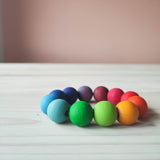 Nahaufnahme des Grimms Baby Greifling Perlenring in Regenbogenfarben von der Seite. Die Holzmaserung ist unter der bunten Lasur gut zu erkennen.