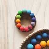 Grimms Baby Greifling Perlenring in Regenbogenfarben in einer kleinen Schale liegend.