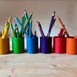 Grapat Becher in sechs Regenbogenfarben, darin, farblich sortiert Farbstifte.