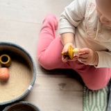 Ein Baby hält den gelben Deckel von Grapat Little Things Wunschdose in der Hand und betrachtet ihn ganz genau.