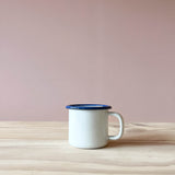 Eine weißer Tasse aus Emaille mit blauem Rand von Kokomoo.