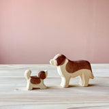 Eine kleiner Bernhardiner sieht zum großem Bernhardiner auf. Beide sind Spielfiguren aus Holz von Ostheimer.