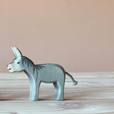 Der graue Esel "Bremer", eine Spielfigur als Holz steht auf einer hellen Holzplatte und schaut nach links. 
