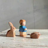 drei holzspielfiguren von Ostheimer stehen nebeneinander mit Blick nach recht. Ein Hase mit stehenden Ohren, ein kleiner Zwerg mit Rucksack und Kappe und ein kleines Häschen.