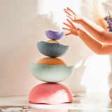 Stapelstein® Inside Regenbogen pastell Set zu einem Turm gebaut, Kinderhände darüber.