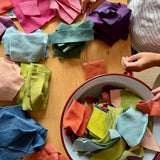 Filzreste in verschiedenen Farben liegen in farblich sortierten Paketen auf dem Tisch, daneben eine große Emaille Schüssel mit mehr bunten Resten aus Filz.