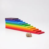 Grimms Regenbogen Bauplatten in rechteckiger Form übereinander gestapelt zu einer Pyramide, im Vordergrund als Größenvergleich das Haus einer Weinbergschnecke.