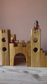 Ritterburg Holzbausteine von Bauspiel aufgebaut als kleine, quadratische Burg, mit zwei Figuren darauf.