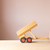 Der Fagus Anhänger für den Muldenkipper aus Holz, seitlich, angehängt an eine Zugmaschine, die Ladefläche in der dritten Position, steil hochgekippt.