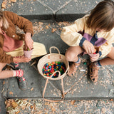 Zwei Kinder sitzen auf Steinstufen, zwischen ihnen ein großer Korb voll mit Grapat Mandalas "Rainbow Flowers".