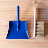 Ein 22 cm kleiner Handbesen aus Holz  mit Naturborsten zum Kehren für Kinder und eine kleine blaue Kehrschaufel aus Metall.