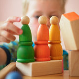 Ein Kind spielt mit den grünen, orangen und gelben Nins und Mates von Grapat und stapelt diese.