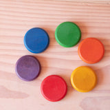 Die Grapat Coins Holzplättchen in den sechs bunten Regenbogenfarben liegen im Kreis.