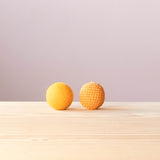 Ein gelber Filzball von Kokomoo neben einem gleich großen gelben Häkelball von Kokomoo, beide haben einen Durchmesser von 5 Zentimeter.