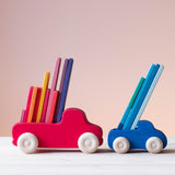 Grimms großer Lastwagen in rot und Grimms kleiner Lastwagen in blau transportieren bunte, flache Holzbausteine von Grimms.