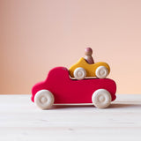 Grimms großer Lastwagen in rot, auf der Ladefläche steht das kleine gelbe Cabrio Holzauto von Grimms.