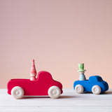 Grimms großer Lastwagen in rot und Grimms kleiner blauer Lastwagen mit jeweils einer zauberhaften Holzfigur als Fahrer.